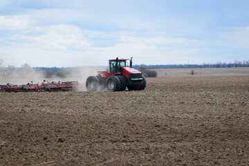 Obraz premium Red tractor with a plow on an agricultural field. work in the field with a big tractor. modern red tractor in the agricultural field. mechanism, Tractor plowing land. Harvester sowing wheat.