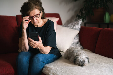 Senior lady in her 70's using mobile phone at home