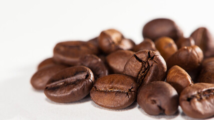 black coffee beans on a white background. Close-up of roasted coffee beans heap isolated on white. aromatic morning drink, invigorating black coffee. macro photo, close-up, on a white background