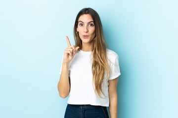 Fototapeta premium Young caucasian woman over isolated background intending to realizes the solution while lifting a finger up