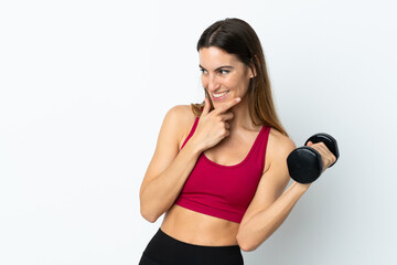 Fototapeta premium Sport woman making weightlifting isolated on white background thinking an idea and looking side