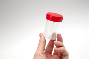 Doctor holding empty sample cup. Plastic container for medical tests.
