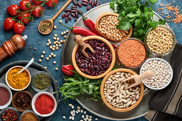 Legumes, lentils, chickpea, beans assortment, tasty appetizing ingredients spices grocery for cooking healthy kitchen on black table. Weight loss diet and fight against cholesterol concept. Top view.