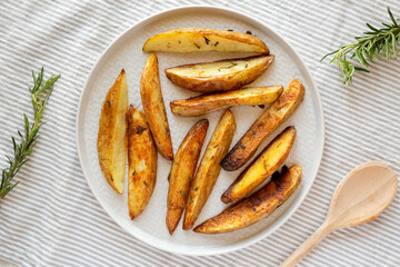 Homemade Rosemary Potato Wedges on a plate, overhead view. Flat lay, top view, from above.