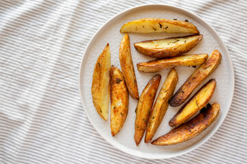Homemade Rosemary Potato Wedges on a plate, top view. Flat lay, overhead, from above. Copy space.