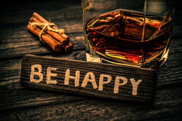 Glass of brandy with cinnamon sticks tied with jute rope and the wooden plank on it is an...