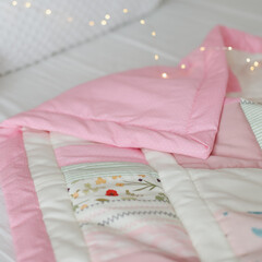 Cozy baby cot with pink patchwork blanket. Baby bedding. Bedding and textile for nursery. Nap and sleep time