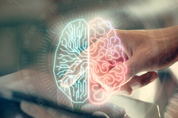 Double exposure of man's hand holding and using a digital device and brain hologram drawing. Data...