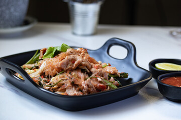 Dried sukiyaki and pork in a black plate with sukiyaki sauce