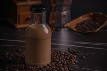 Instant coffee in a clear glass bottle with dark coffee beans.