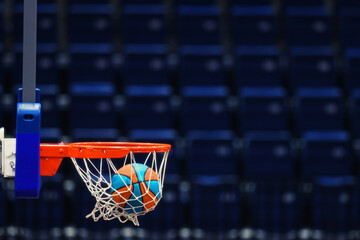 Basketball hoop with a ball on the background of the empty seats of the sports arena