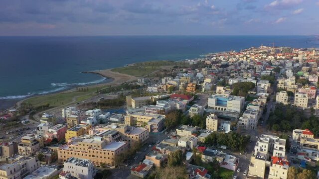 Aerial Panning Shot Of Coastal City By Sea Against Cloudy Sky At Sunset, Drone Flying Over Residential District - Jaffa, Israel