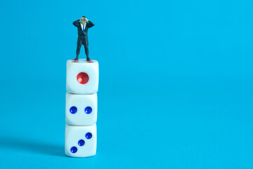 Businessman using binoculars standing above three dice stack. Miniature tiny people toys photography. isolated on blue background.