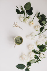 A cup of matcha tea and roses on white background. Flatlay, top view