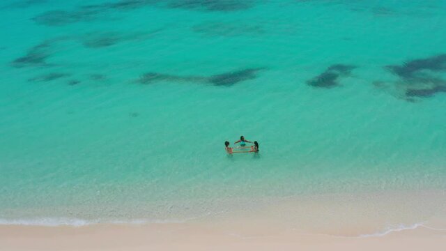 Overhead view of three women tourists enjoying turquoise ocean of Pedernales. Aerial