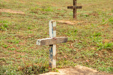 Duas cruzes cravadas no chão sobre túmulos em cemitério.
