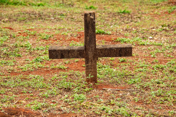 Uma cruz cravada no chão gramado sobre um túmulo.