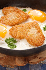 Fried eggs with slices of bread in the shape of a heart in the frying pan