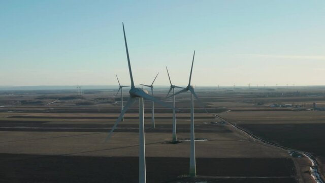 drone approaching a huge wind turbine from the front axis and the sun is nicely back