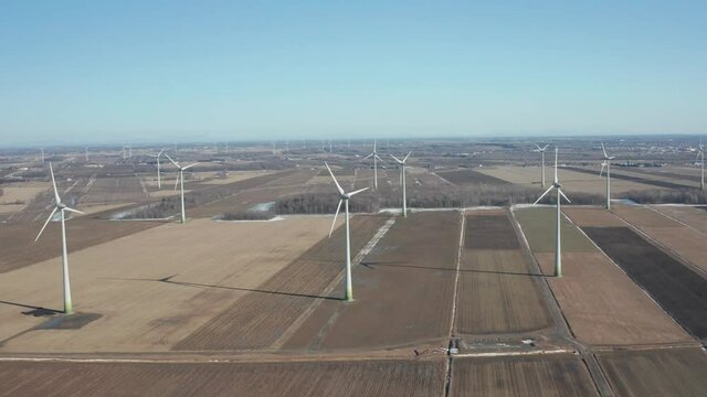 drone going around a wind farm at the begining of winter with a sunny day in a huge wind farm