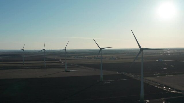 drone sidemove looking front of wind turbines in a field nice sun back