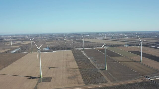 drone moving forward in a wind farm turbines in a sunny day begining winter