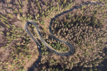 Aerial view of mountain road during springtime. Cars driving in the mountain winding road cutting through the forest. Mountain landscape above the road that leads to Poiana Brasov, Romania