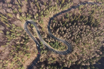 Foto op Aluminium Aerial view of mountain road during springtime. Cars driving in the mountain winding road cutting through the forest. Mountain landscape above the road that leads to Poiana Brasov, Romania © alexionutcoman