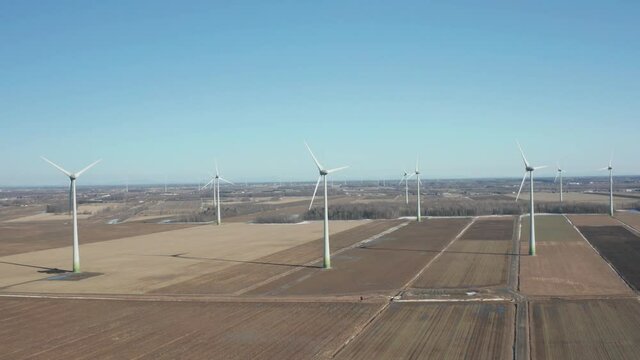 drone ascending to overlook a wind turbine field in a sunny day at the beginning of winter.