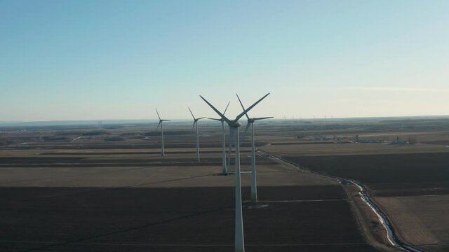 drone going around a huge wind farm overlooking the front axis of the turbines in a sunny day