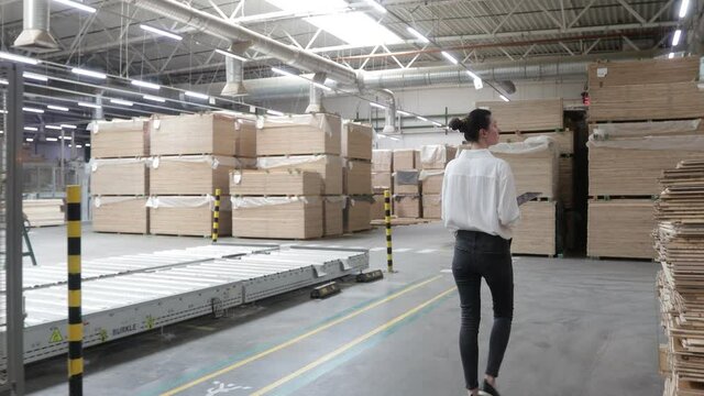 Business woman in Industrial Carpentry factory - production of wooden boards with modern machines. Modern robotic factory indoors. Woodworking production.