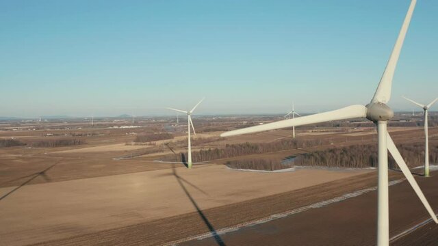 drone movind sideways into the front of a wind turbine in a sunny day