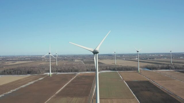 drone in a wind farm approaching to a wind turbine from the back to a close distamce in a sunny day but begining of winter