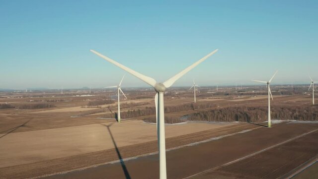 drone approaching a wind farm turbines from the back part to a very close distance in a sunny day