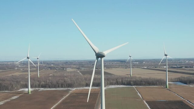 drone flying in a wind farm approaching a wind turbine front the back at the same high as the rotor, giving a nice perspective in a sunny day