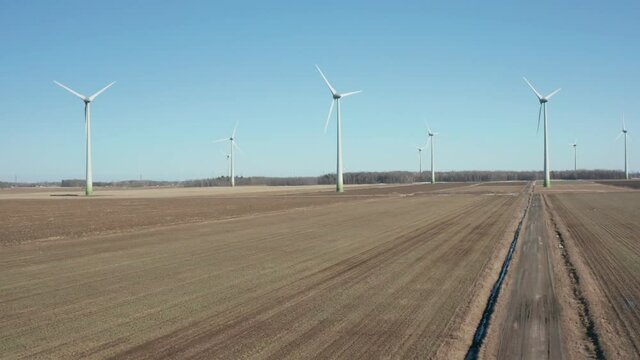 drone ascending overlooking a wind farm in a sunny day at the beginning of winter with clear sky