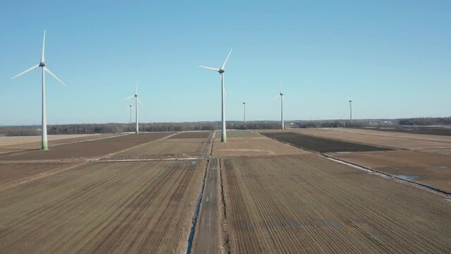 drone going up overlooking a wind farm in a sunny day begining winter