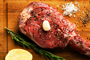 Raw beef steak on a wooden cutting board on black background - 431522579