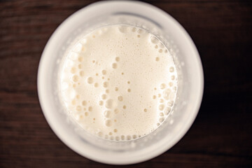 Top view of a glass with vanilla milkshake, frothy cocktail with foam and bubbles