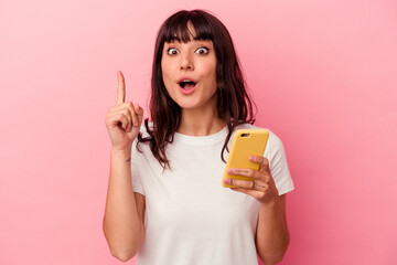 Young caucasian woman holding a mobile phone isolated on pink background having an idea, inspiration concept.