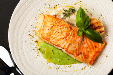 Grilled salmon with sauce and spices on a white plate on a dark background - 431523338