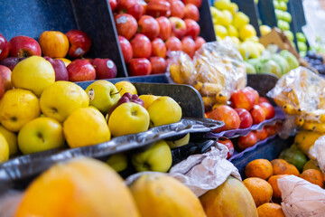 Close-up of colorful fruit stand with apples, small bananas, and more