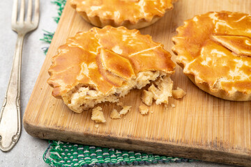 Homemade chicken pies over wooden board with vintage fork
