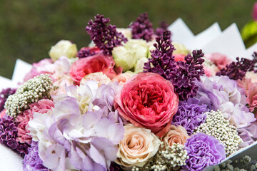 Wedding bouquet of tree pink peony, purple carnations, blue hydrangea, lilac, wrapped in craft paper