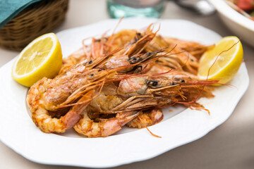 Baked prawns with lemon halves on a white plate.