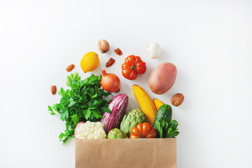 Healthy food background. Healthy vegan vegetarian food in paper bag vegetables and fruits on white,...