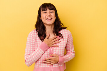 Fototapeta premium Young caucasian woman isolated on yellow background laughs happily and has fun keeping hands on stomach.