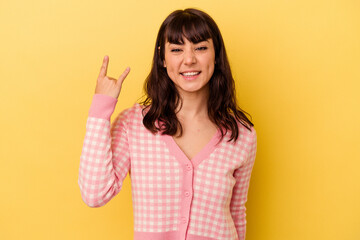 Young caucasian woman isolated on yellow background showing rock gesture with fingers