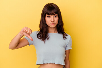 Young caucasian woman isolated on yellow background showing a dislike gesture, thumbs down....