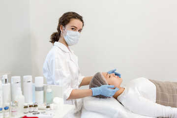 Beautician in a mask makes a facial massage in a beauty salon